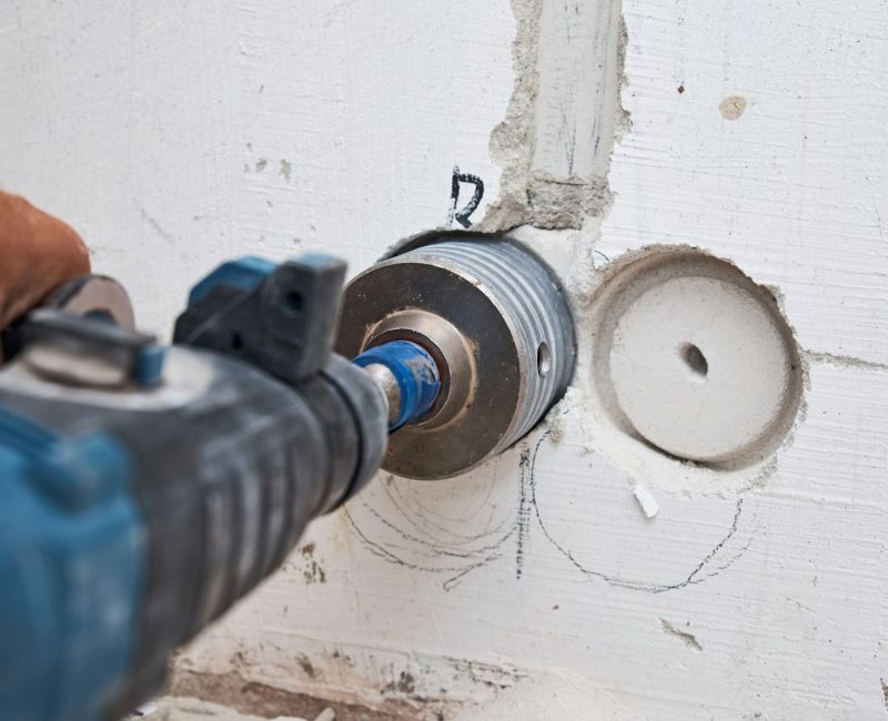 Builder with hummer drill perforator drills hole in a wall